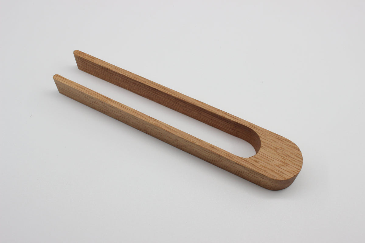 Solid oak toaster tongs showing curved sprung design