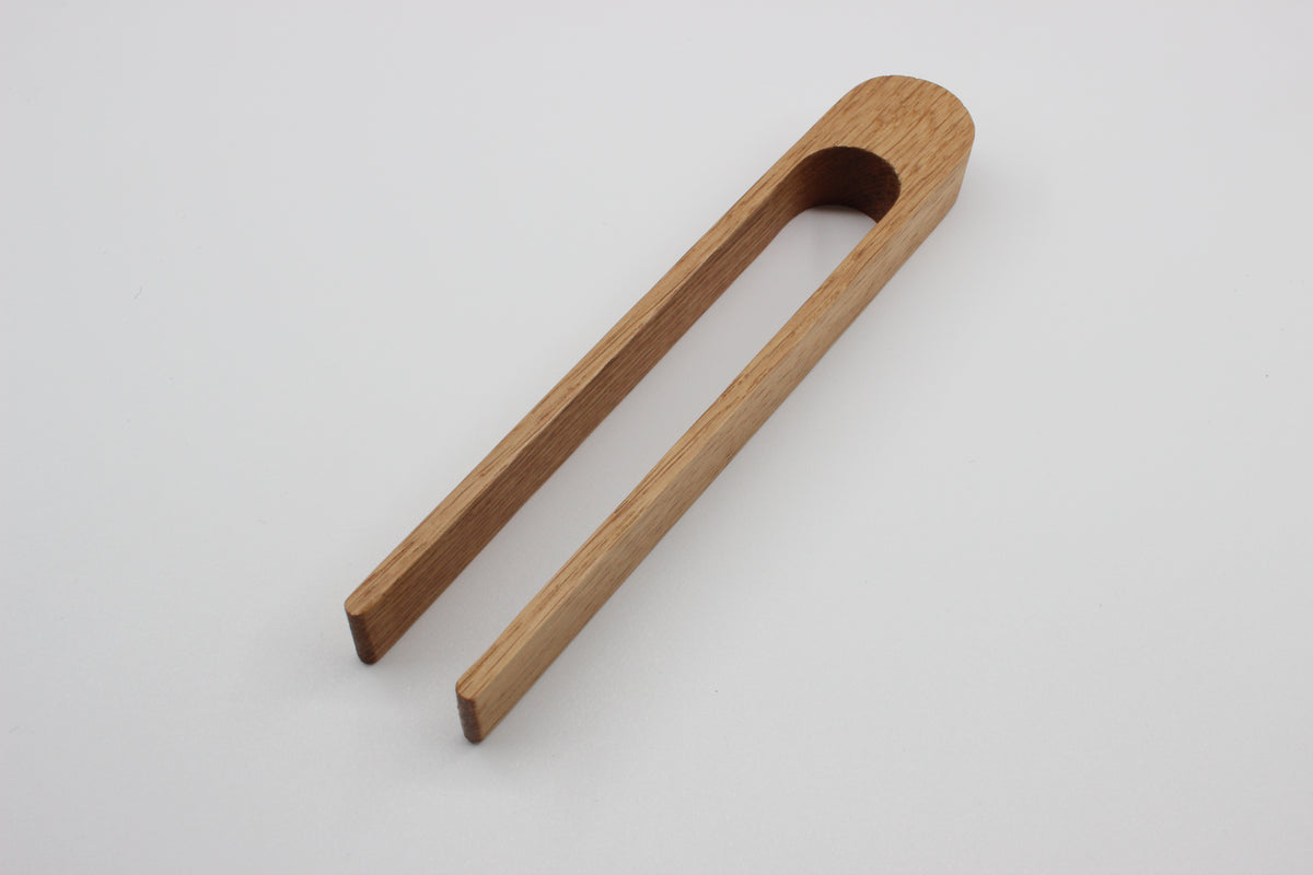 Solid oak toaster tongs showing hanging hole and natural wood grain